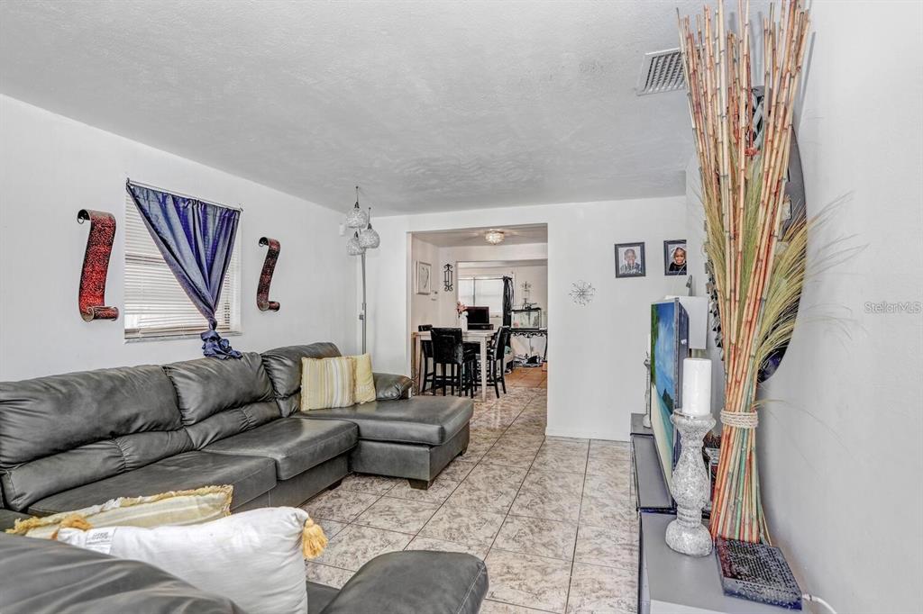 A living room features a grey sectional sofa, tiled floors, and a view into a dining area — 4833 ASHLAND DRIVE, TAMPA, FL