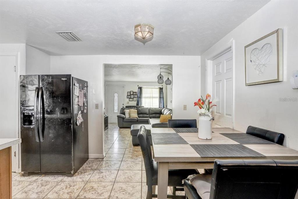 A dining area with a table and chairs sits adjacent to a kitchen and living room — 4833 ASHLAND DRIVE, TAMPA, FL