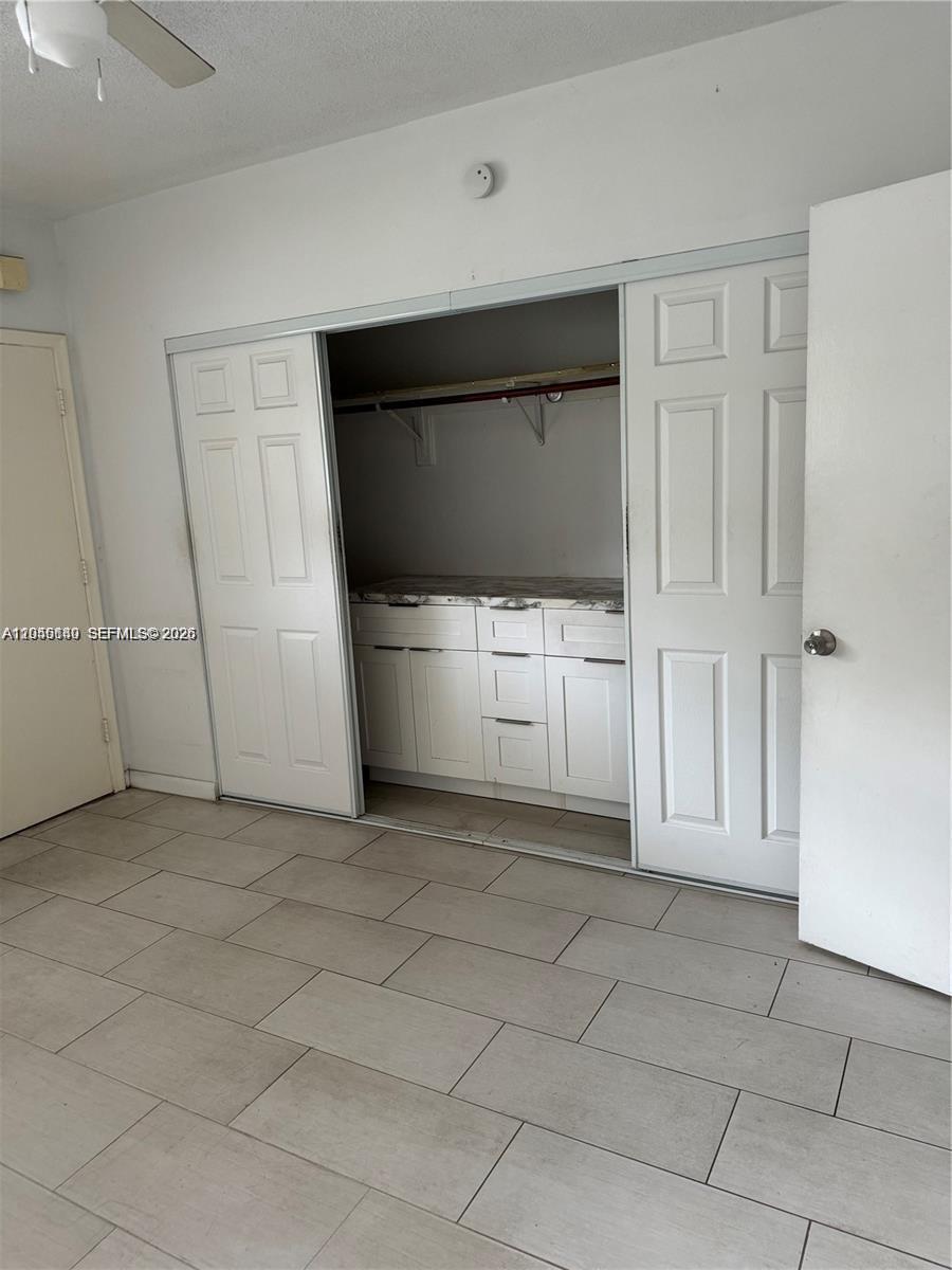 A room features light-colored tile flooring and a closet with white cabinetry and sliding doors — 285 NE 191st St # 2907, Miami FL 33179, MIAMI, FL
