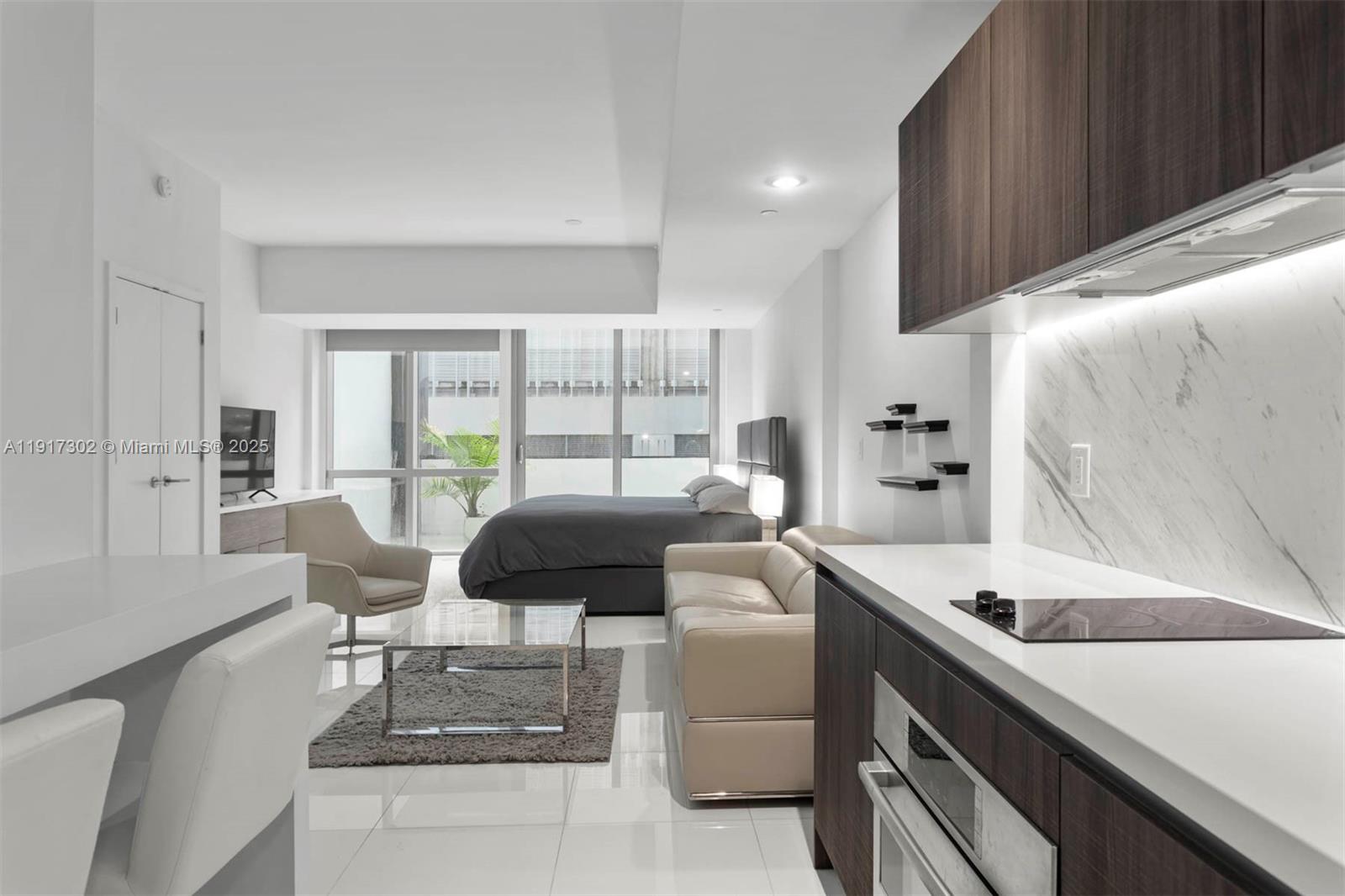A modern studio apartment features a kitchen, living area, and bedroom with white tile floors — 851 NE 1st Ave # 300, Miami FL 33132, MIAMI, FL