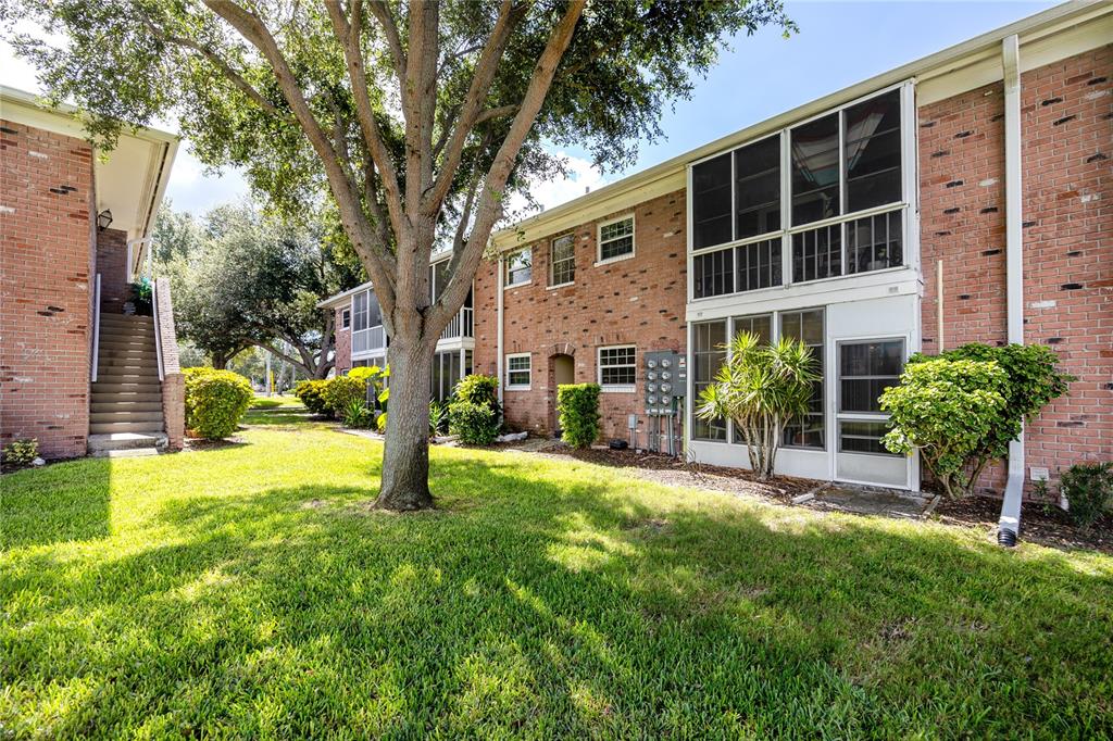 A two-story brick apartment building with screened-in porches and a large tree on the lawn — 3435 41ST TERRACE S UNIT 198, ST PETERSBURG, FL