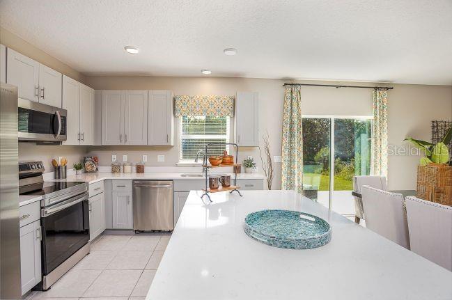 A kitchen features light gray cabinets, stainless steel appliances, and a large white island — 31576 WILD GRAPE LANE, BROOKSVILLE, FL