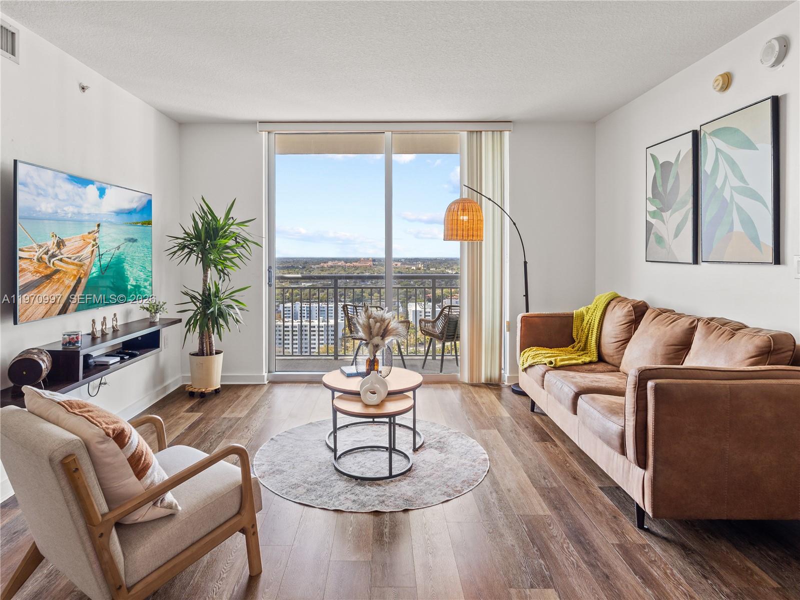 A living room features a brown leather sofa, a beige armchair, and a balcony view — 9066 SW 73rd Ct # 2008, Miami FL 33156, MIAMI, FL