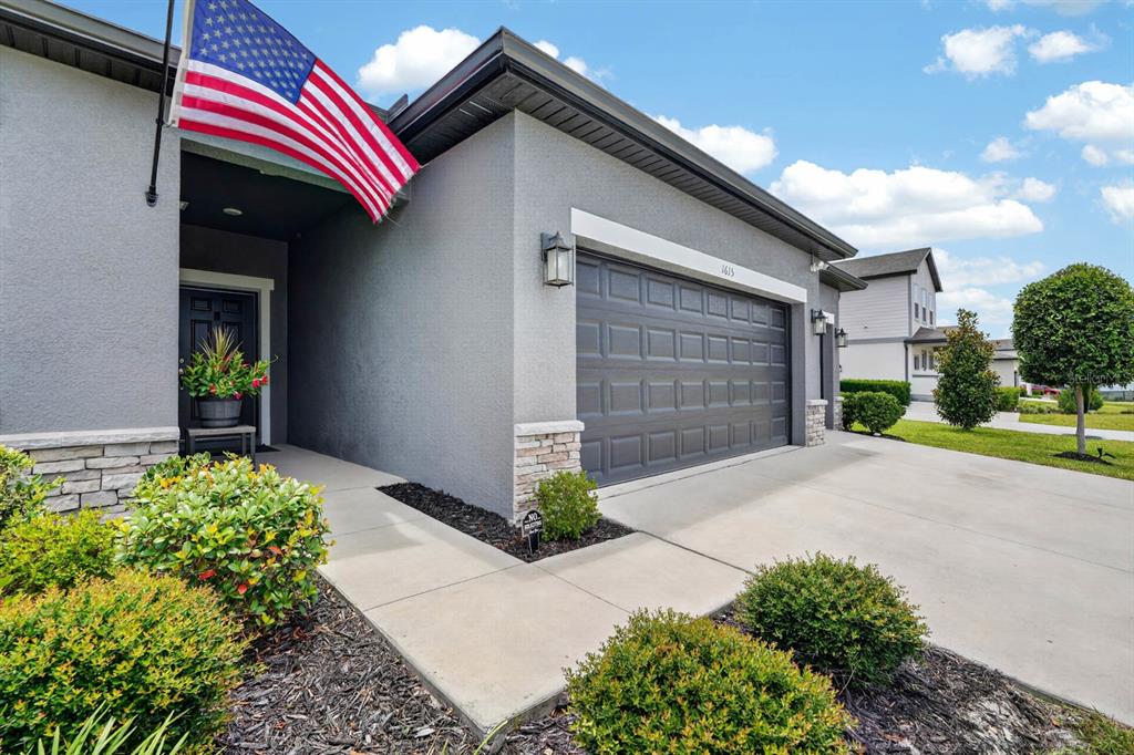 A gray house exterior features a garage, a front entryway, and an American flag — 1615 MEADOWLARK DRIVE, DELTONA, FL
