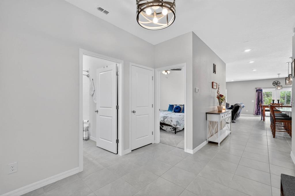 A hallway with tiled floors leads to a bathroom, a bedroom, and an open living area — 1615 MEADOWLARK DRIVE, DELTONA, FL