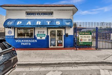 The exterior of a Volkswagen parts shop features a blue awning and a for-sale sign — 2112 NW 36th St, Miami FL 33142, MIAMI, FL