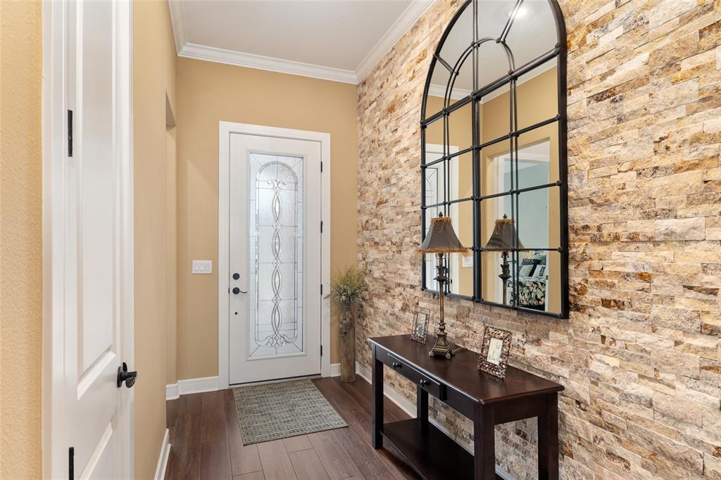 An entryway features a stone accent wall, a large arched mirror, and a dark wood console — 5897 SW 90TH COURT ROAD, OCALA, FL