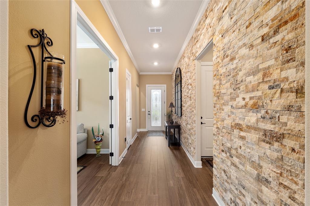 A hallway features wood-look flooring, recessed lighting, and a wall accented with stacked stone veneer — 5897 SW 90TH COURT ROAD, OCALA, FL
