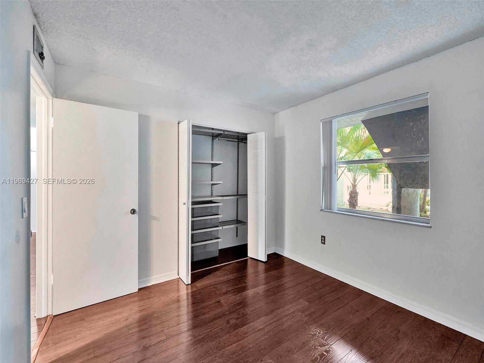 A bedroom features white walls, dark wood flooring, a closet with shelving, and a window — 4600 SW 67th Ave # 155, Miami FL 33155, MIAMI, FL