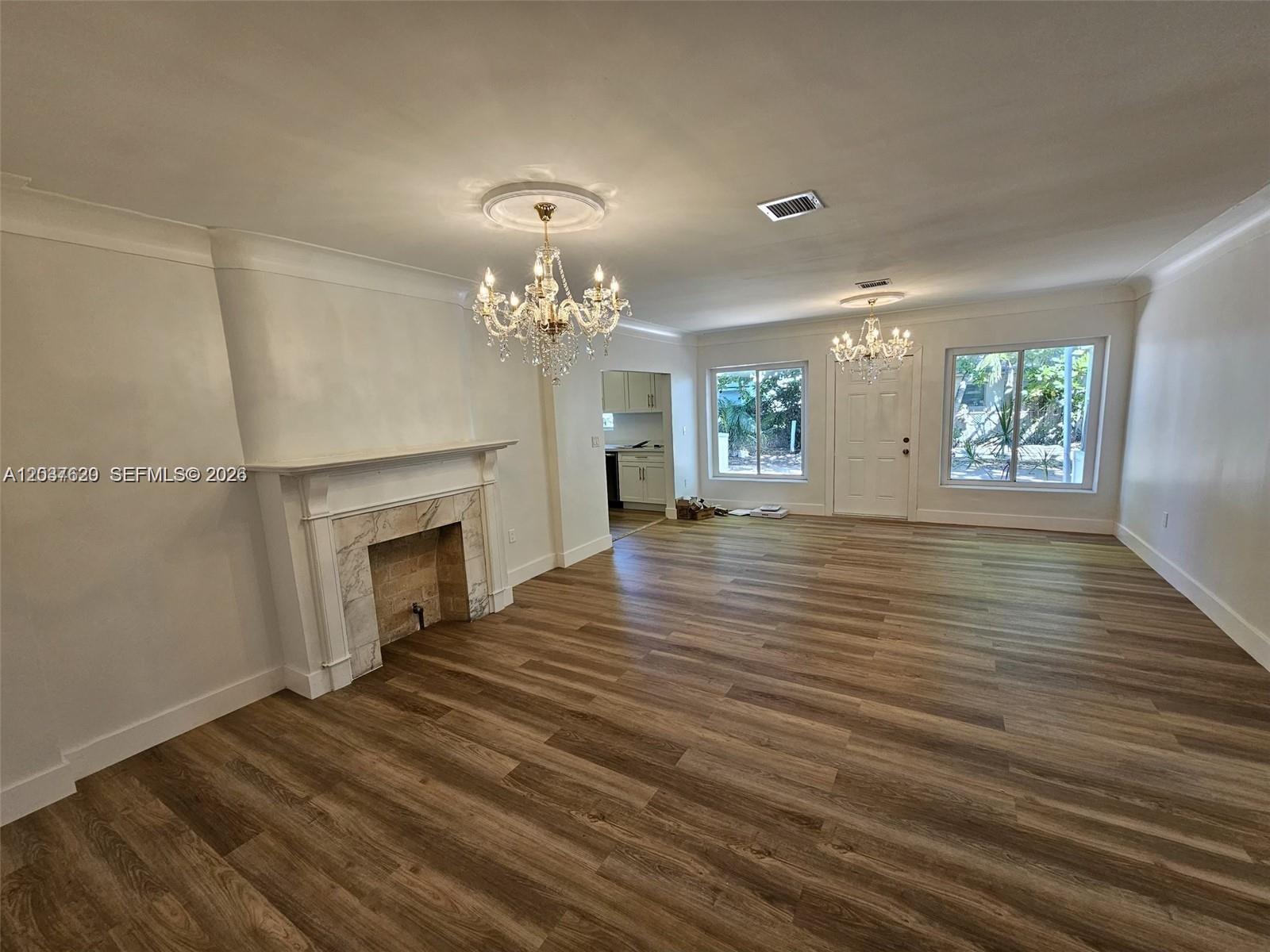 A living room features a fireplace, two crystal chandeliers, and light wood-look flooring — 1915 Normandy Dr, Miami Beach FL 33141, MIAMI BEACH, FL