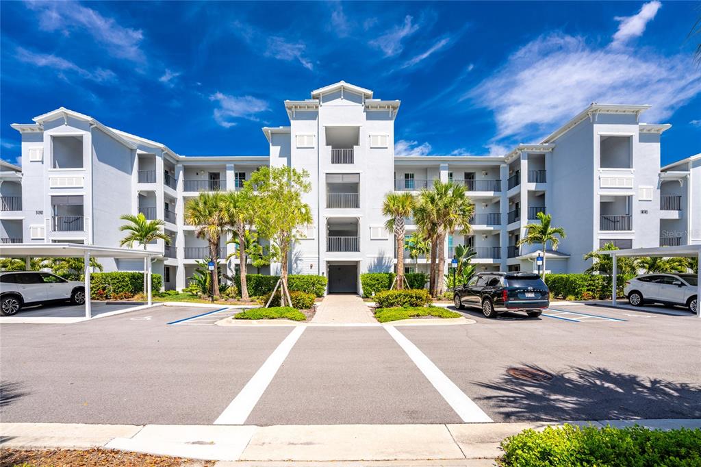 A multi-story apartment building with a central entrance, palm trees, and a parking lot — 14141 HERITAGE LANDING BOULEVARD UNIT 921, PUNTA GORDA, FL
