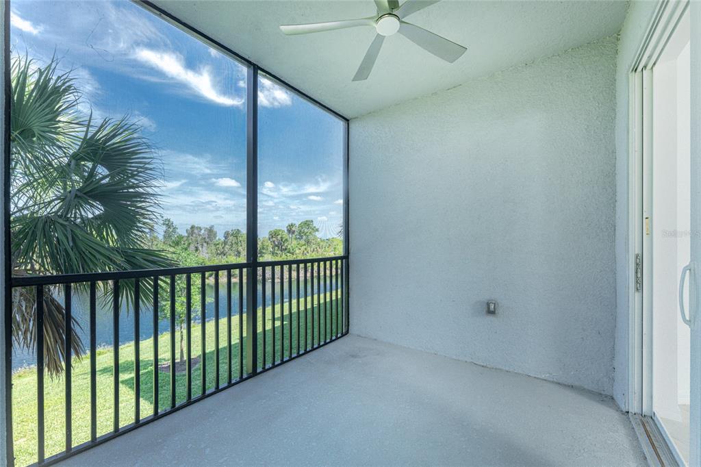 A screened-in balcony with a ceiling fan overlooks a grassy lawn and a pond — 14141 HERITAGE LANDING BOULEVARD UNIT 921, PUNTA GORDA, FL