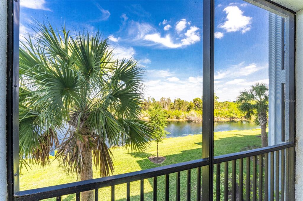 A view of a lake and palm trees from a screened-in balcony — 14141 HERITAGE LANDING BOULEVARD UNIT 921, PUNTA GORDA, FL