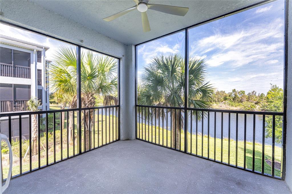 A screened-in balcony features a ceiling fan, concrete flooring, and views of palm trees and water — 14141 HERITAGE LANDING BOULEVARD UNIT 921, PUNTA GORDA, FL