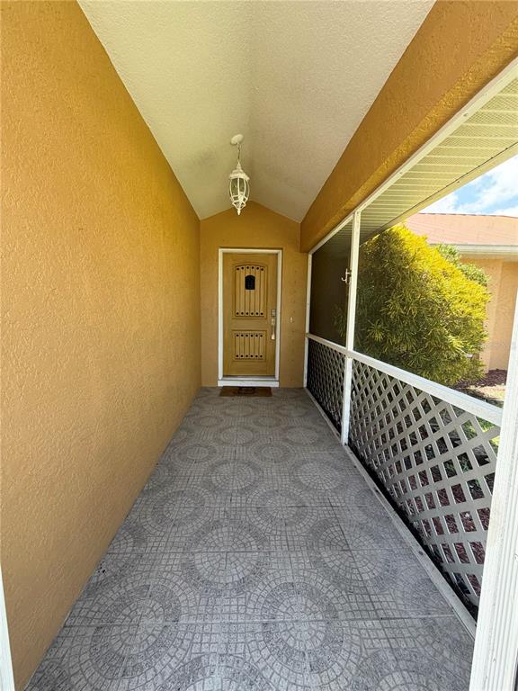 A covered entryway features a patterned tile floor, a yellow door, and a screened enclosure — 27019 SHANAHAN LANE, PUNTA GORDA, FL
