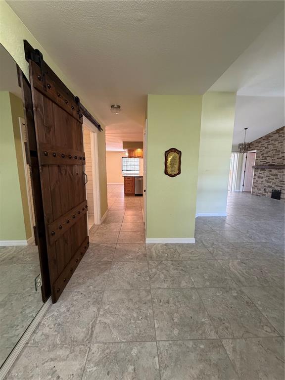 A view of a tiled hallway featuring a rustic wooden barn door and light-colored walls — 27019 SHANAHAN LANE, PUNTA GORDA, FL