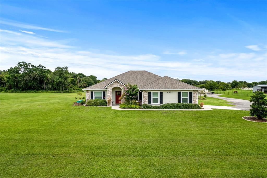 A backyard features a trampoline on a grassy lawn enclosed by a wooden fence — 3088 WAINWRIGHT STREET, DELTONA, FL