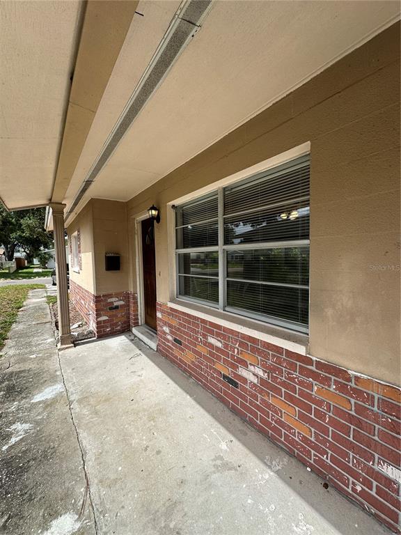 A concrete porch leads to a front door and a window with horizontal blinds — 473 93RD AVENUE N, ST PETERSBURG, FL
