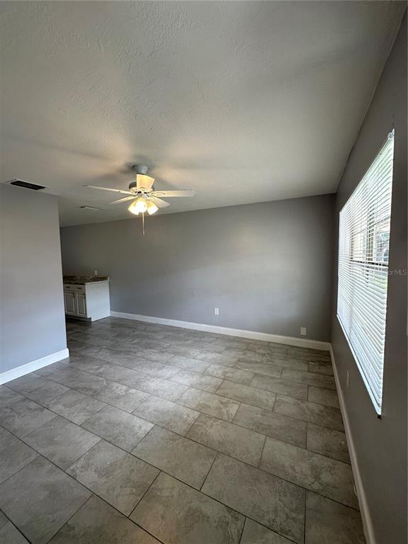 A living room with gray walls, tile flooring, a ceiling fan, and a window with blinds — 473 93RD AVENUE N, ST PETERSBURG, FL