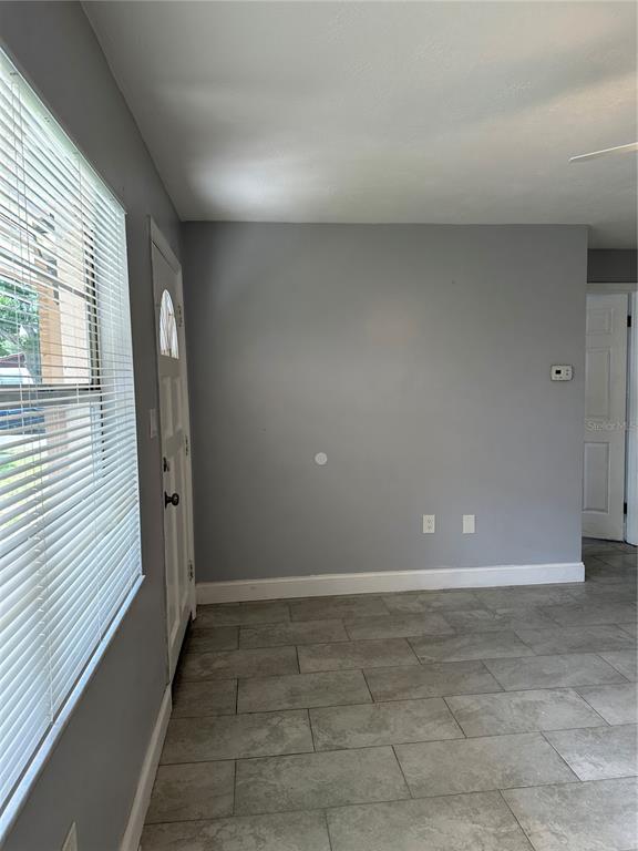A room with gray walls, tile flooring, a window with blinds, and a white door — 473 93RD AVENUE N, ST PETERSBURG, FL