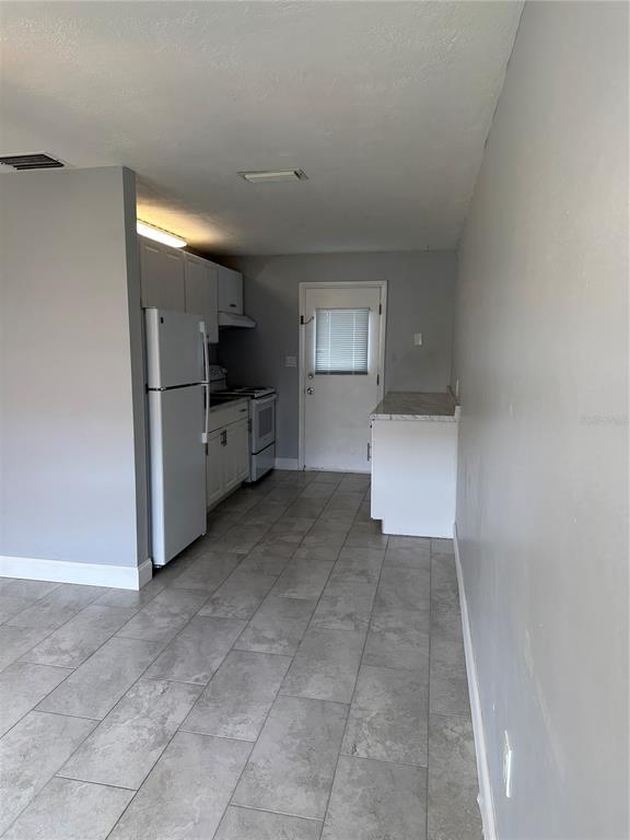 A kitchen features gray walls, tile flooring, white cabinets, and a white refrigerator — 473 93RD AVENUE N, ST PETERSBURG, FL