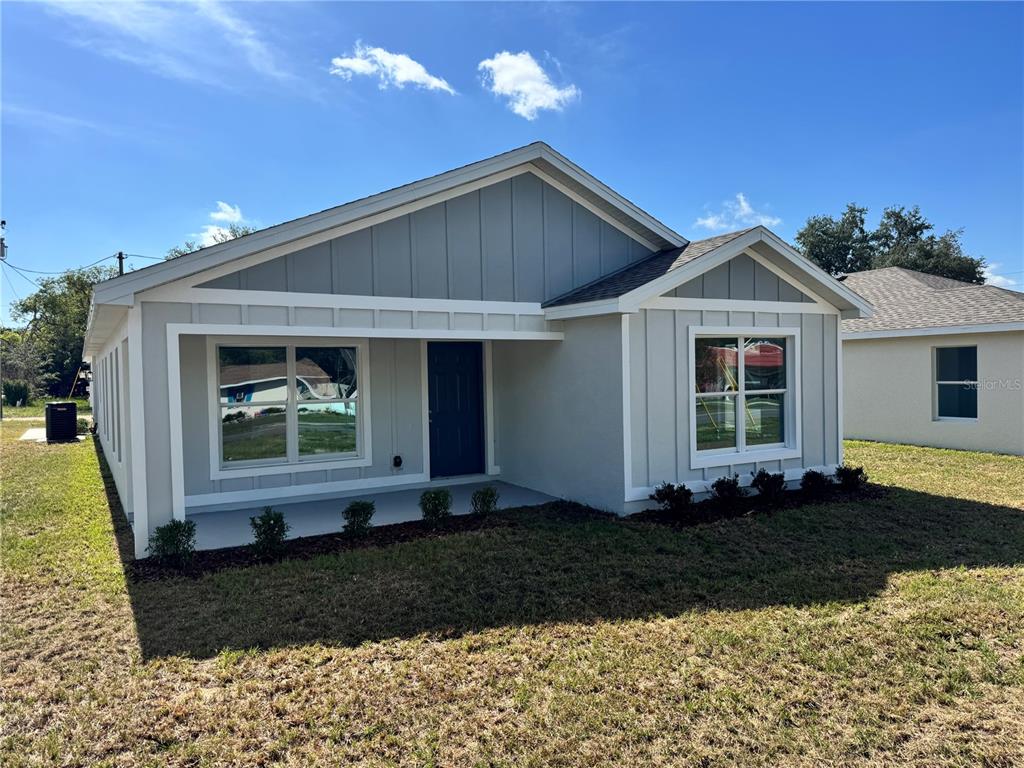 A single-story house with gray board-and-batten siding and a covered front porch — 6024 12TH STREET, ZEPHYRHILLS, FL
