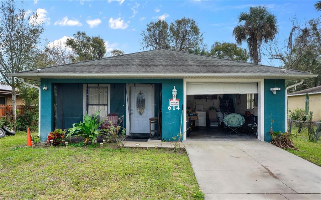 A teal single-story house with a front porch, an attached garage, and a concrete driveway — 614 WASHINGTON STREET, NEW SMYRNA BEACH, FL