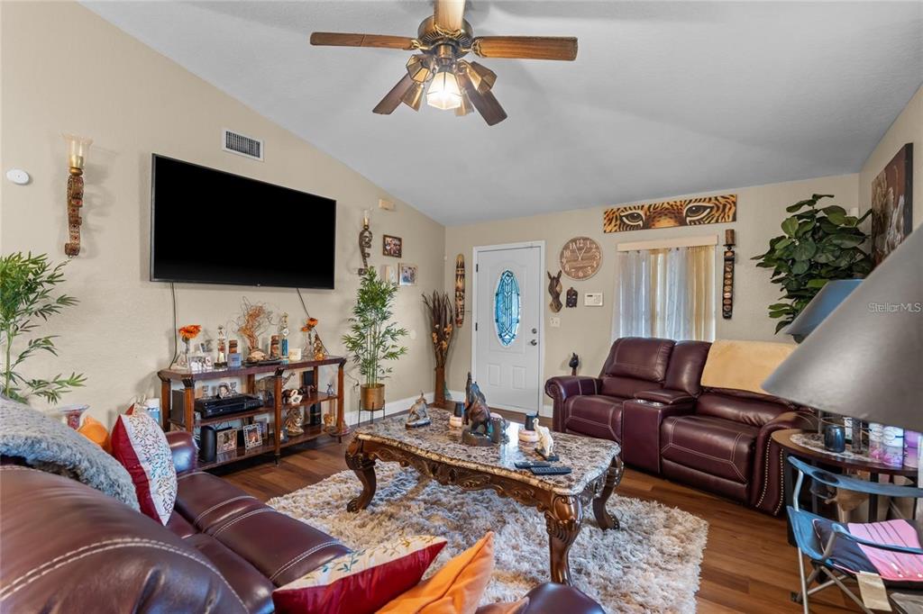 A living room features a vaulted ceiling, leather sofas, a marble coffee table, and a television — 614 WASHINGTON STREET, NEW SMYRNA BEACH, FL