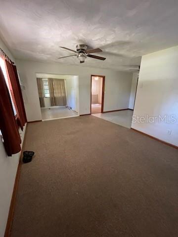 A living room with beige carpet, a ceiling fan, and doorways leading to other rooms — 4316 SW DEEPWATER COURT, DUNNELLON, FL