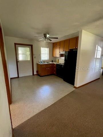 A kitchen with wooden cabinets, black appliances, and a light-colored floor next to a door — 4316 SW DEEPWATER COURT, DUNNELLON, FL