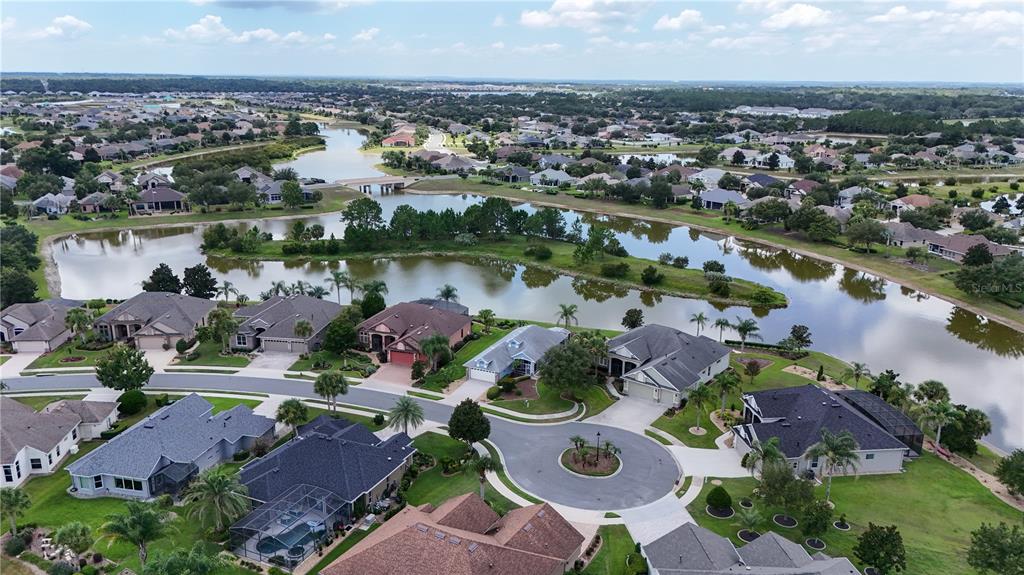 An aerial view shows a suburban neighborhood with houses surrounding a large, winding lake — 2416 BAR HARBOR, MOUNT DORA, FL