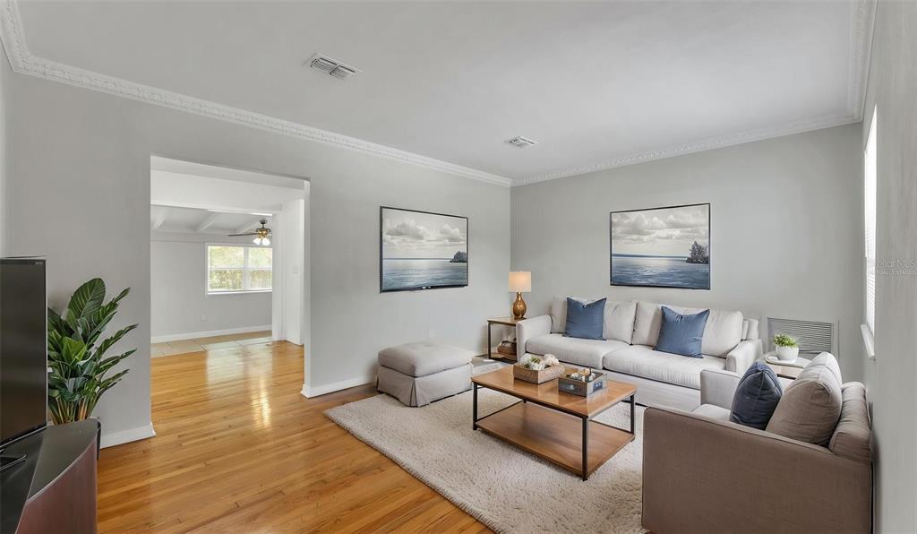 A living room features hardwood floors, a light gray sofa, and two framed ocean prints — 614 W SHADY LANE, LAKELAND, FL