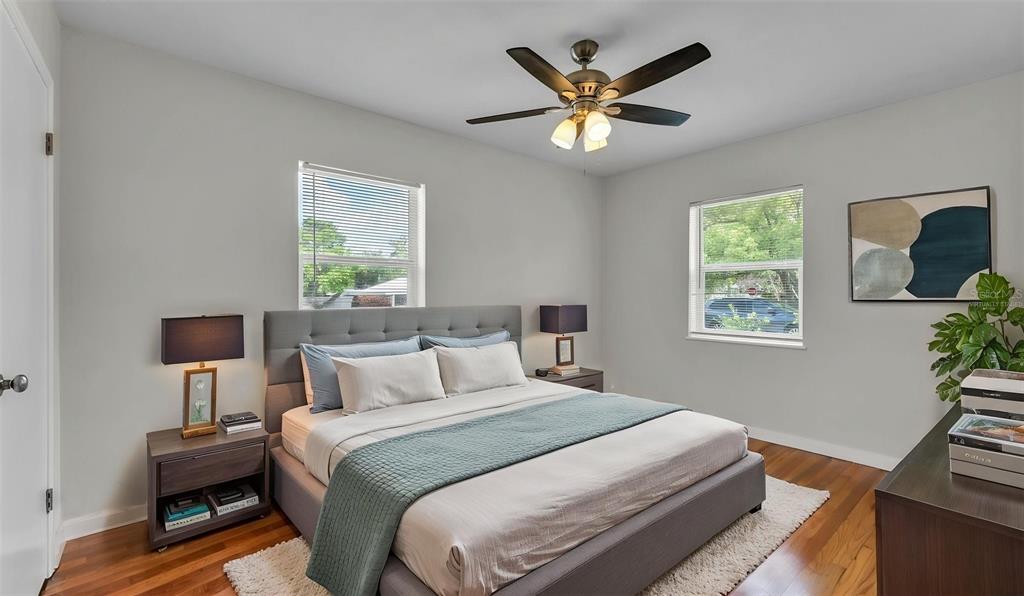 A bedroom features a gray upholstered bed, hardwood floors, two windows, and a ceiling fan — 614 W SHADY LANE, LAKELAND, FL