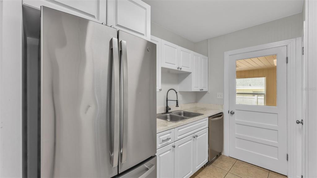 A kitchen features white cabinets, stainless steel appliances, a double sink, and a glass-paneled door — 614 W SHADY LANE, LAKELAND, FL