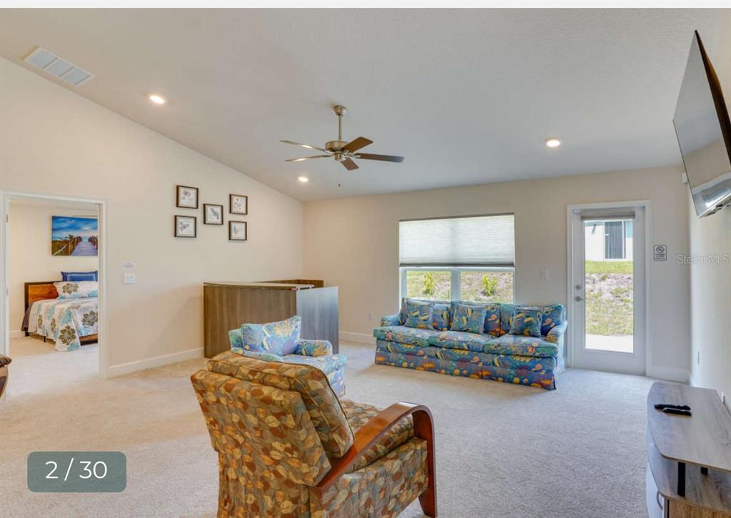 A living room with carpeted floors, a patterned sofa, an armchair, and a ceiling fan — 303 SHAD WAY, POINCIANA, FL