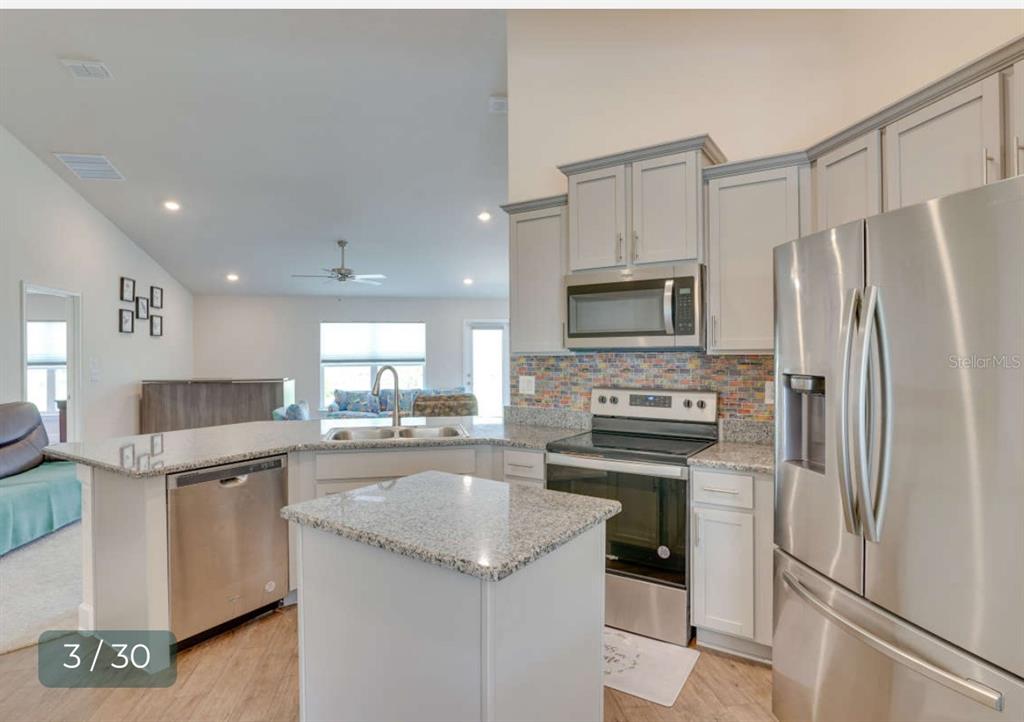 A kitchen with stainless steel appliances, granite countertops, and light gray cabinetry — 303 SHAD WAY, POINCIANA, FL