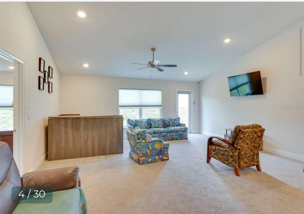 A living room with carpeted floors, a ceiling fan, a bar, and patterned furniture — 303 SHAD WAY, POINCIANA, FL