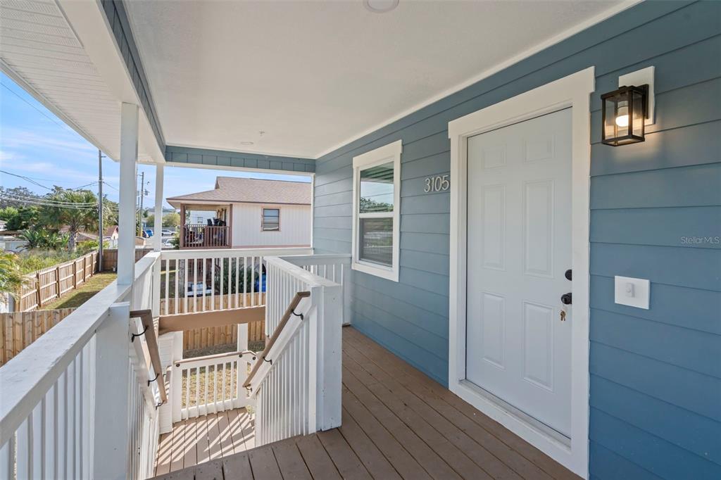 An elevated wooden porch with blue siding, a white front door, and a staircase — 3103 16TH STREET N, ST PETERSBURG, FL