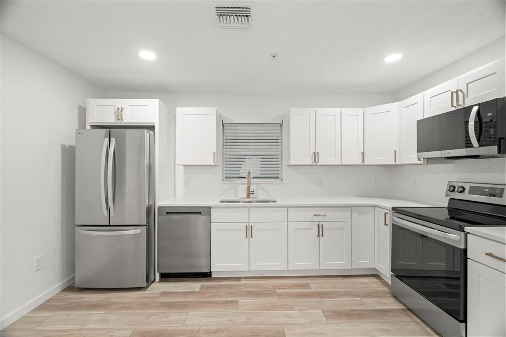 A kitchen with white cabinets, stainless steel appliances, and light wood-look flooring — 3103 16TH STREET N, ST PETERSBURG, FL