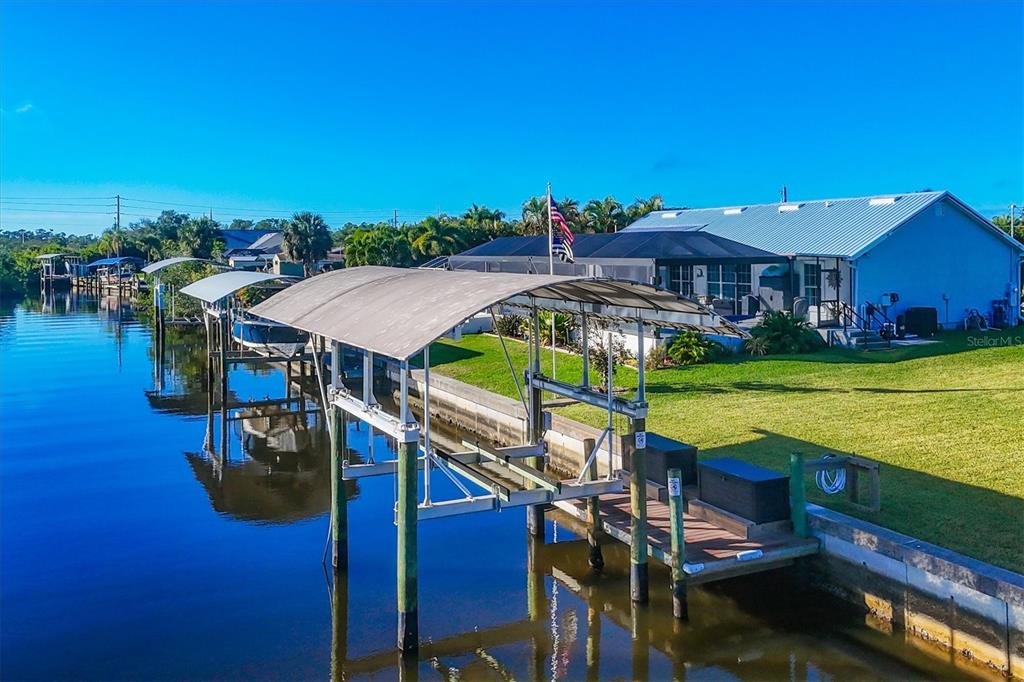 An aerial view of a canal-front home featuring a boat lift and a screened lanai — 5276 EARLY TERRACE, PORT CHARLOTTE, FL
