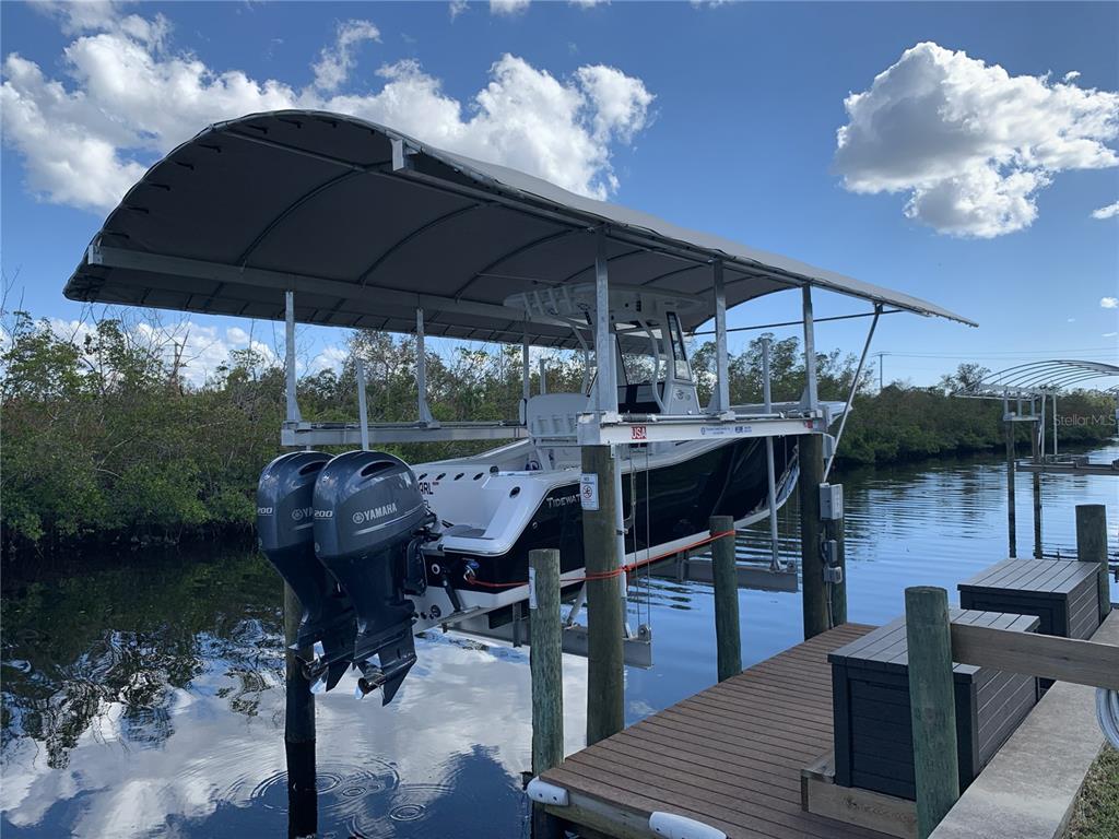 A boat on a mechanical lift under a canopy at a wooden dock — 5276 EARLY TERRACE, PORT CHARLOTTE, FL