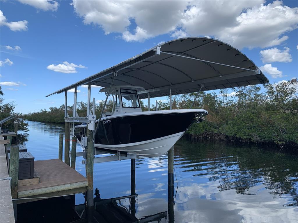 A motorboat is lifted on a boat lift with a canopy over a canal — 5276 EARLY TERRACE, PORT CHARLOTTE, FL