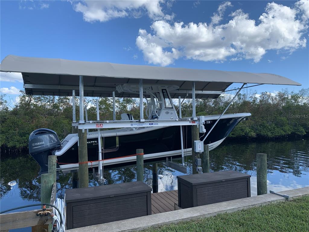 A boat is docked on a lift under a canopy in a canal — 5276 EARLY TERRACE, PORT CHARLOTTE, FL