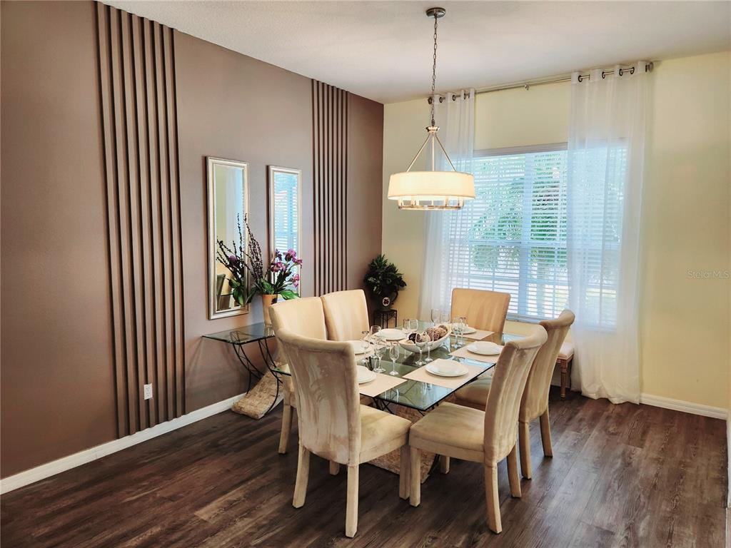 A dining room features a glass-top table, upholstered chairs, and a brown accent wall — 236 BOXWOOD DRIVE, DAVENPORT, FL
