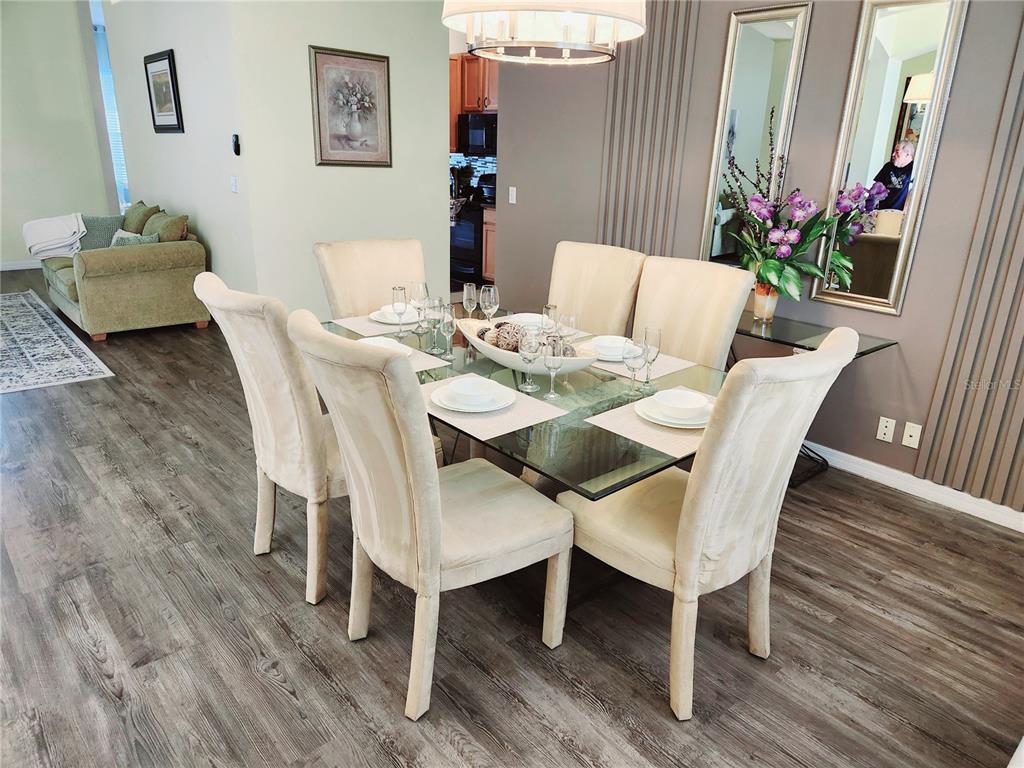 A dining room features a glass-topped table with six upholstered chairs on wood-look flooring — 236 BOXWOOD DRIVE, DAVENPORT, FL