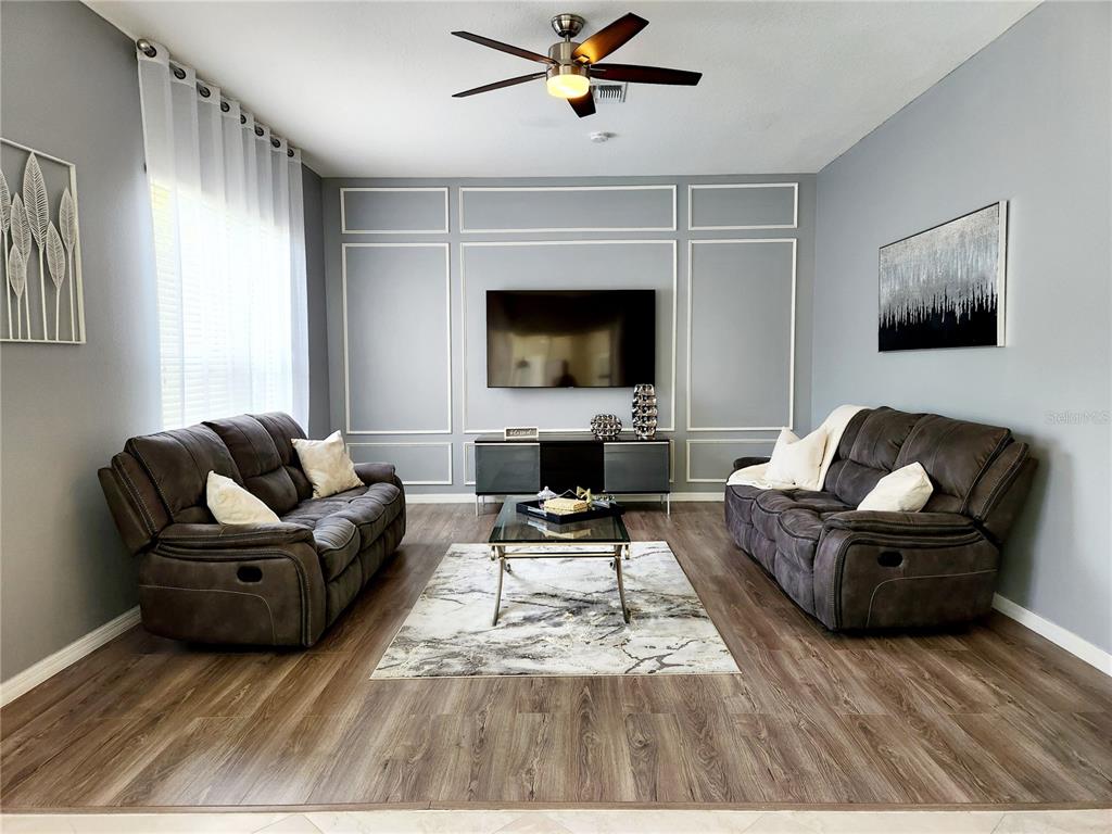 A living room features two dark sofas, a central coffee table, and wall molding — 236 BOXWOOD DRIVE, DAVENPORT, FL