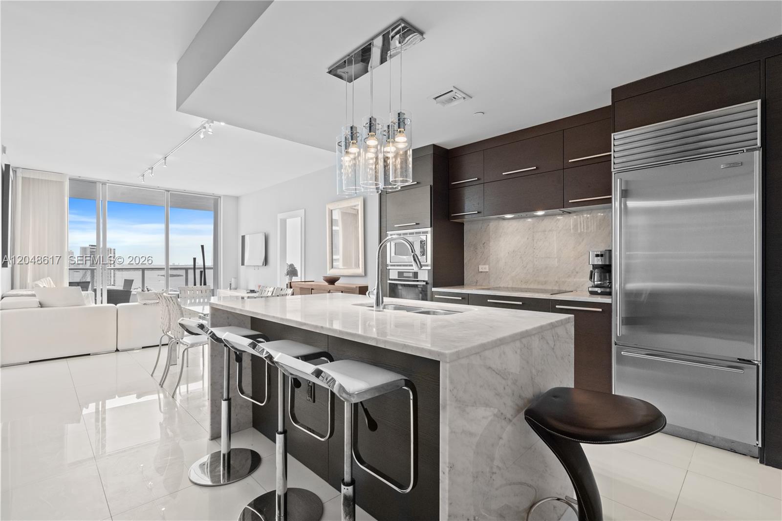 A modern kitchen features a marble-topped island, dark wood cabinetry, and stainless steel appliances — 900 Biscayne Blvd # 2408, Miami FL 33132, MIAMI, FL