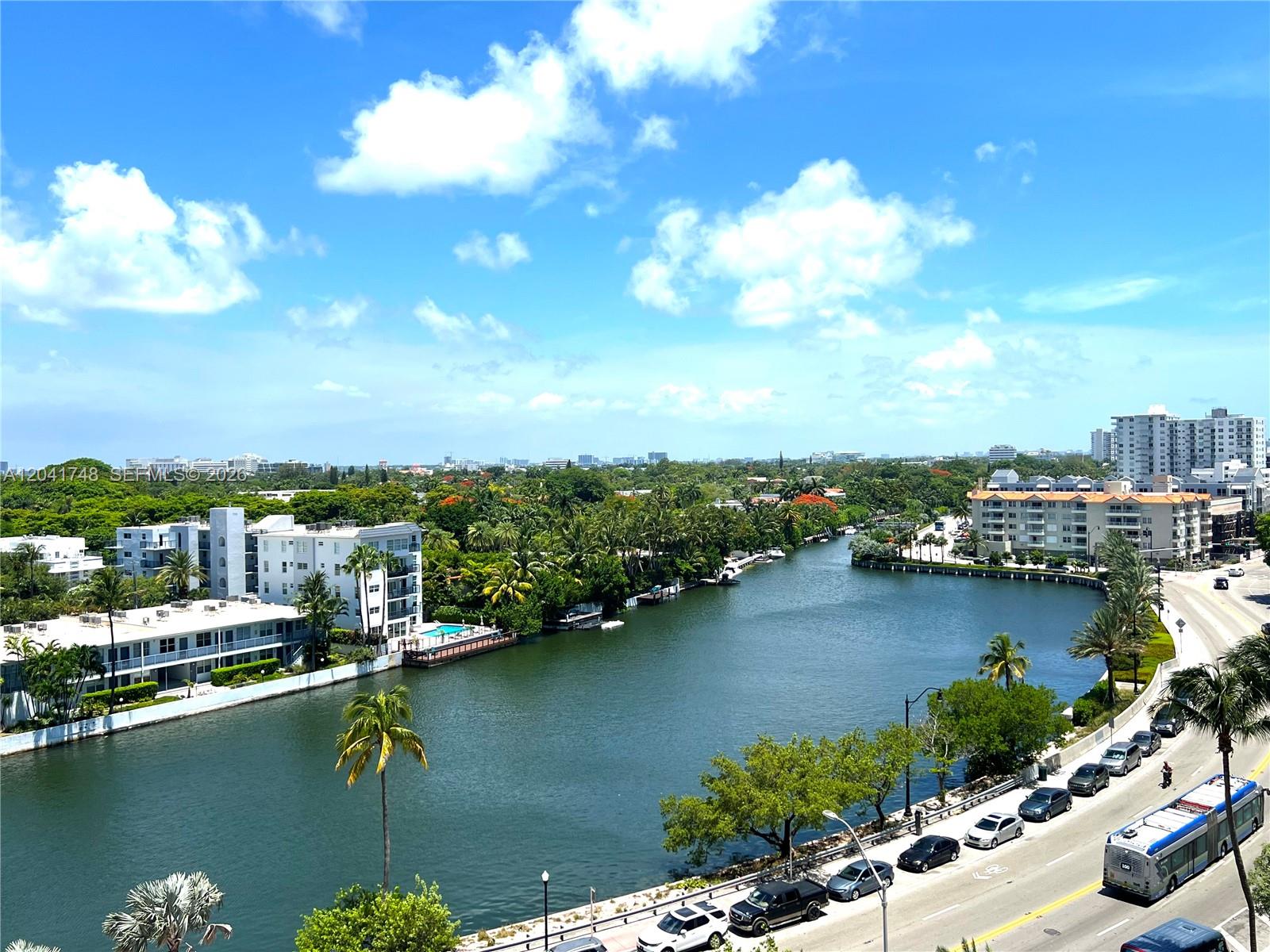 An elevated view of a canal lined with palm trees, apartment buildings, and a road — 2401 Collins Ave # 1009, Miami Beach FL 33140, MIAMI BEACH, FL