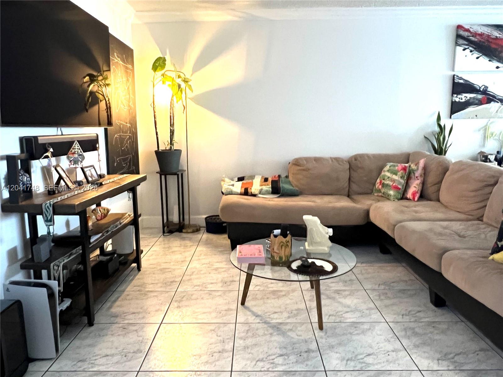 A living room features a beige sectional sofa, a glass coffee table, and a media console — 2401 Collins Ave # 1009, Miami Beach FL 33140, MIAMI BEACH, FL