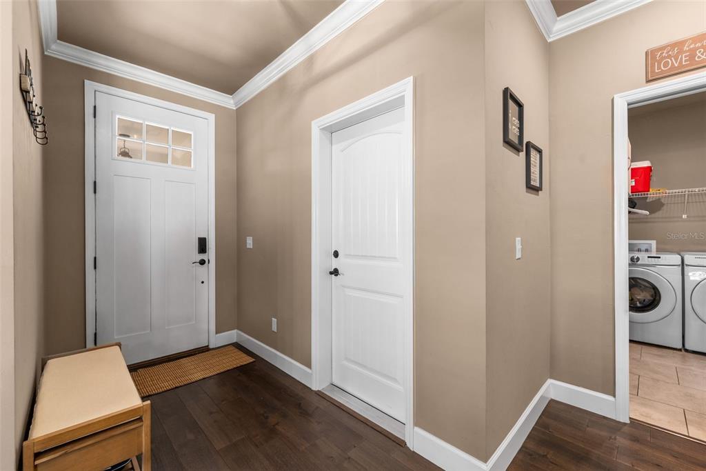 An entryway features a white front door, a wooden bench, and a doorway to a laundry room — 24674 SW 19TH PLACE, NEWBERRY, FL